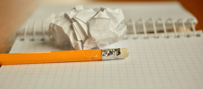 Ein angekauter Bleistift auf einem Block, daneben ein zerknülltes Blatt Papier